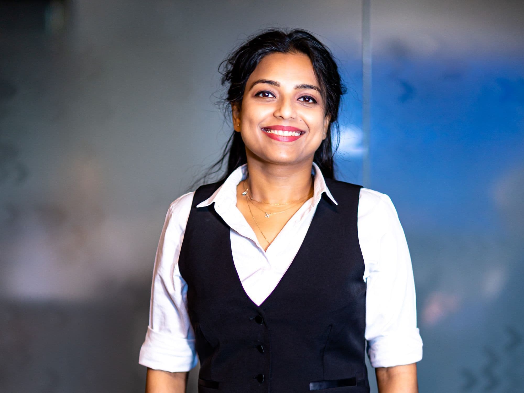 A smiling woman in a white shirt and black vest.